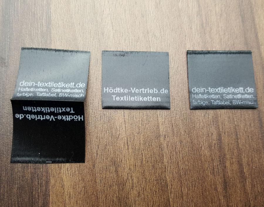 Satin Etiketten, schwarz Seitennahteinnäher Spezielle Anwendungen. Edle Labels mit Logo. Einfarbiger Aufdruck in weiß als Standard. Auf Anfrage auch in Glanz-Gold, Silber oder Grau möglich.