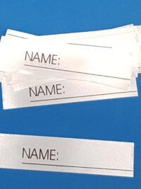 AW-303 25 Stück Textiletiketten mit Aufdruck "Name_______" zum Beschreiben einzeln geschnitten. | Abmessungen: 15x63mm (+/- 1mm) ENR: links | ENR = Einnähraum Zusammensetzung Band: 100% Polyester (Satinband)