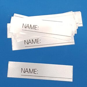 25 Stück Textiletiketten mit Aufdruck "Name_______" zum Beschreiben einzeln geschnitten.   |   Abmessungen: 15x63mm  (+/- 1mm) ENR: links   |   ENR = Einnähraum Zusammensetzung Band: 100% Polyester (Satinband)