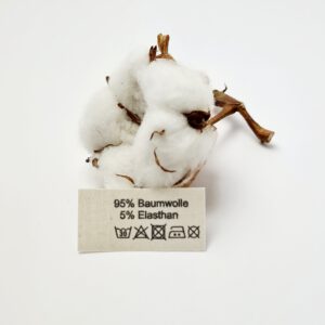 Label aus Naturbaumwollband mit der Aufschrift 95% Baumwolle 5% Elasthan mit Pflegesymbole.