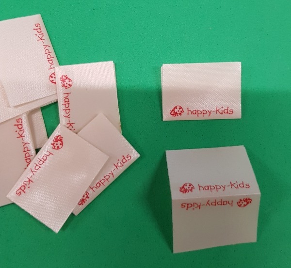 Happy-kids Label mit Marienkäfer - mittig gefalten. Material: Polyestersatin, beige Abmessungen: 25 x 36mm (25x18mm) Ideal für Seitennaht.